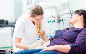 Phlebotomist drawing blood from a female patient in a clinic.